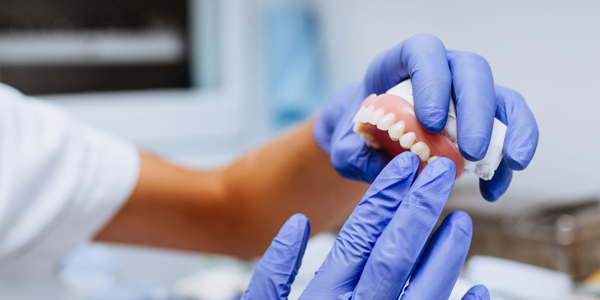 person holding full arch denture